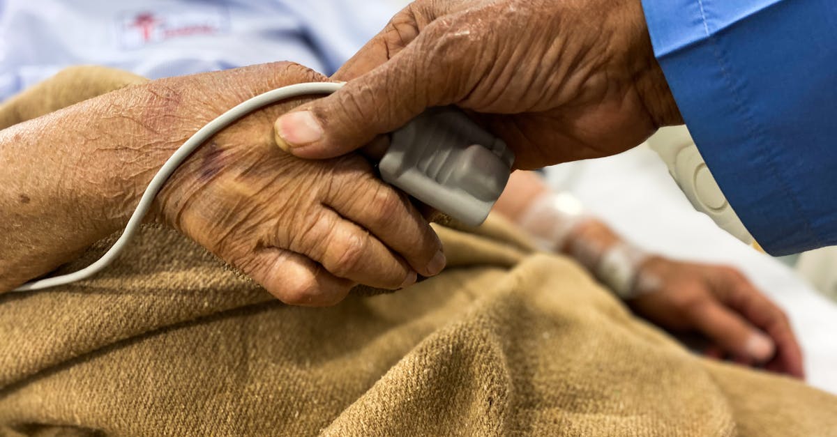 Extremely tender beef at hospital - Crop old female patient lying on medical bed with pulse oximeter on finger and old man holding wrinkled hand