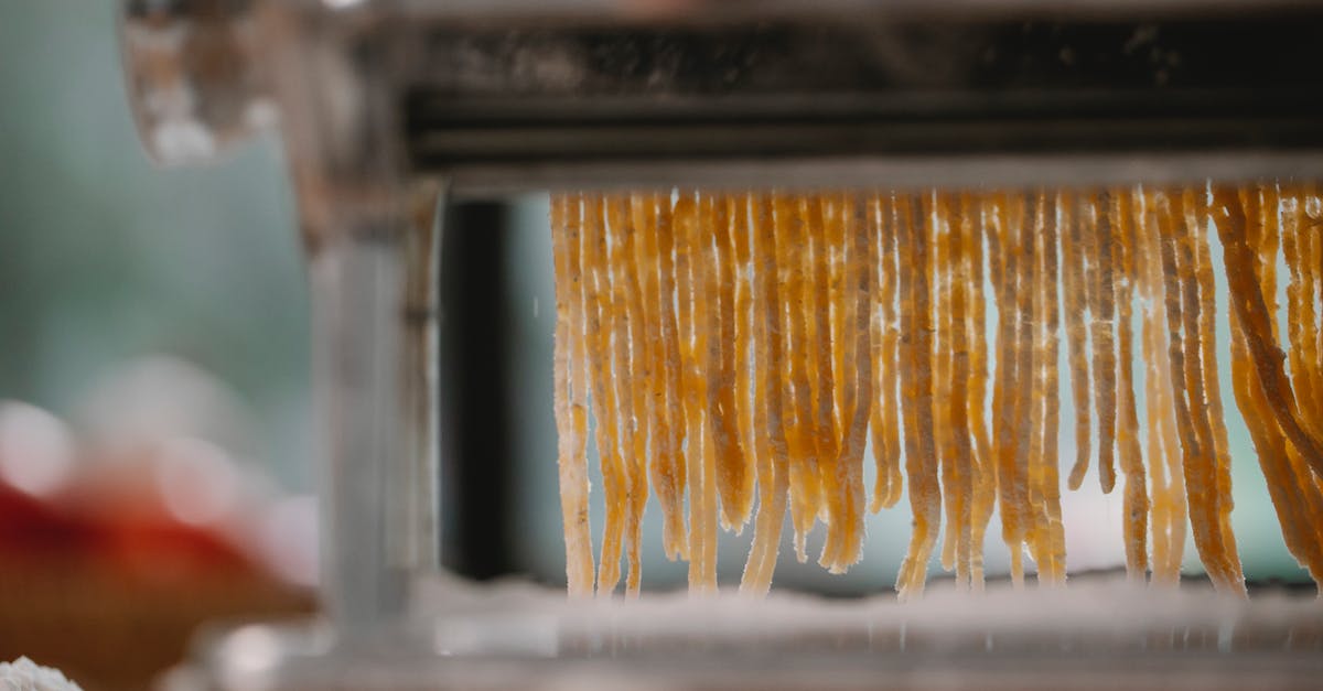 Extrusion pasta maker versus roller: which one makes the best pasta? - Process of cutting pasta with machine on kitchen