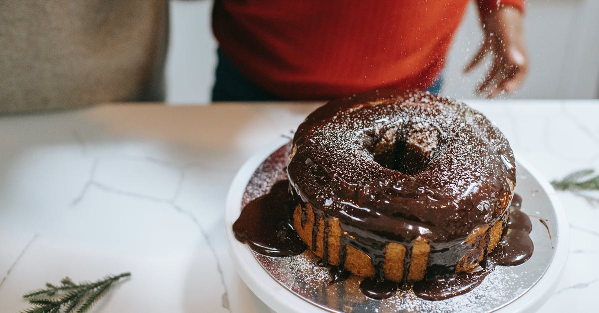 Failed chocolate sponge - From above of crop anonymous parent with black kid pouring powdered sugar on Christmas sponge cake with chocolate glaze