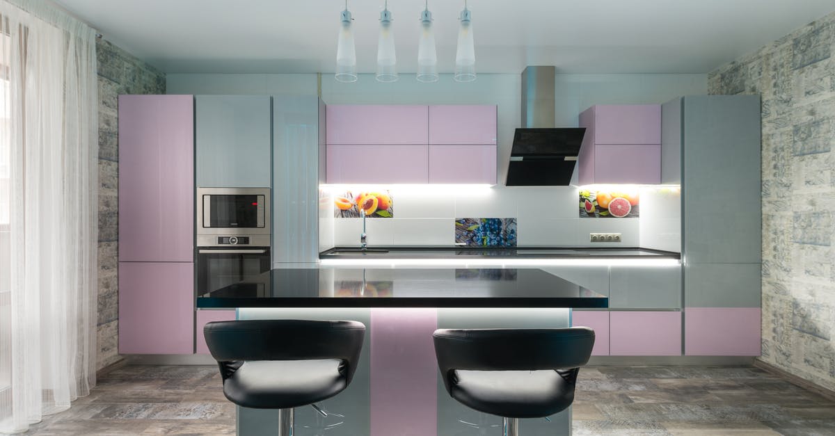 Fan oven temperature conversion and biology/chemistry - Spacious kitchen with black table and chairs placed near colorful cupboards and modern kitchenware in stylish apartment with window and tulle