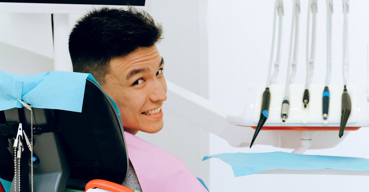 Faster to wet cure in room temp? - Back view of smiling ethnic man sitting in chair of dentist while preparing for treatment in modern clinic and looking over shoulder at camera