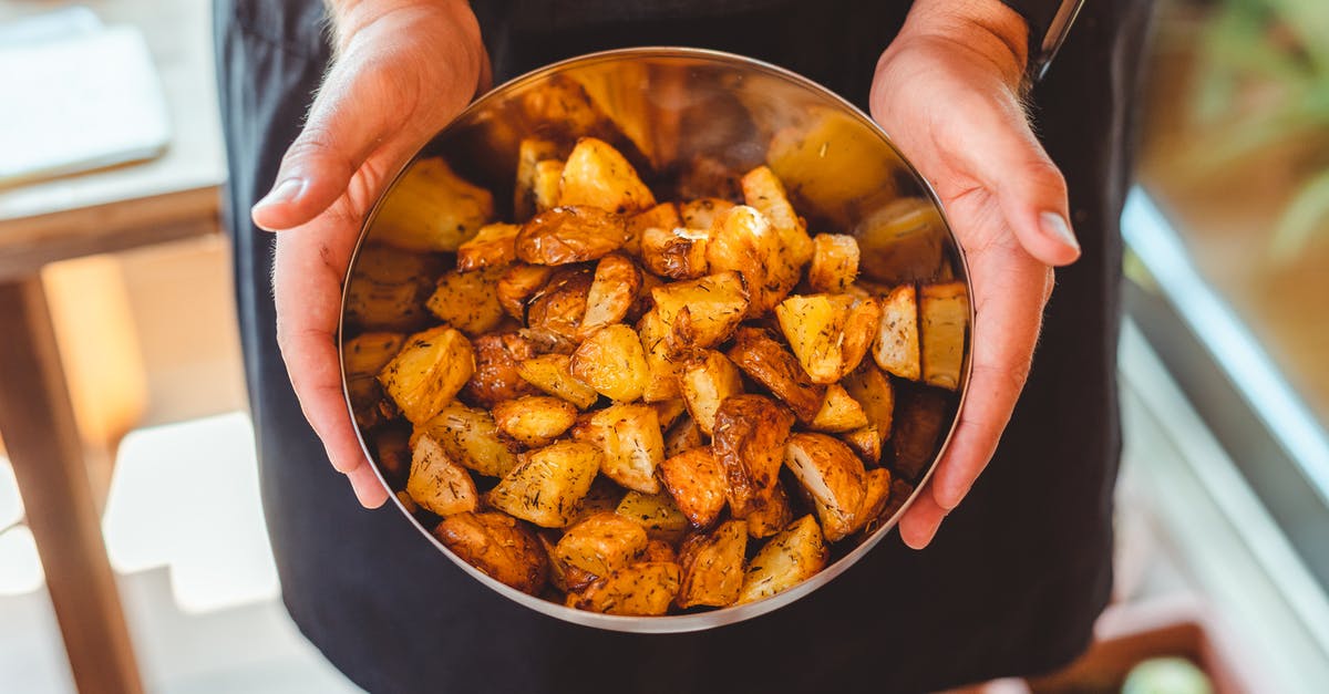 Fastest way to cook a baked potato? - From above of crop anonymous male chef in apron standing with bowl of potato wedges