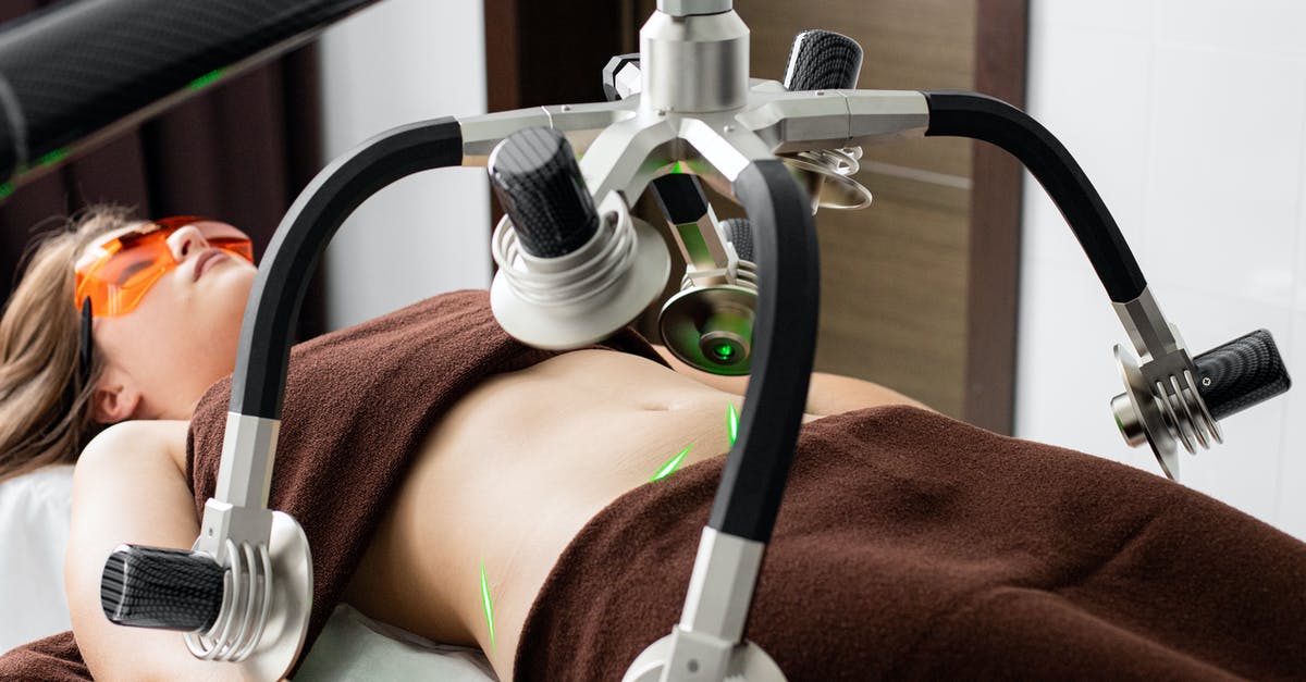 Fat free dumplings? - Female client lying on table under lasers of modern weight loss machine on belly during liposuction procedure in medical clinic