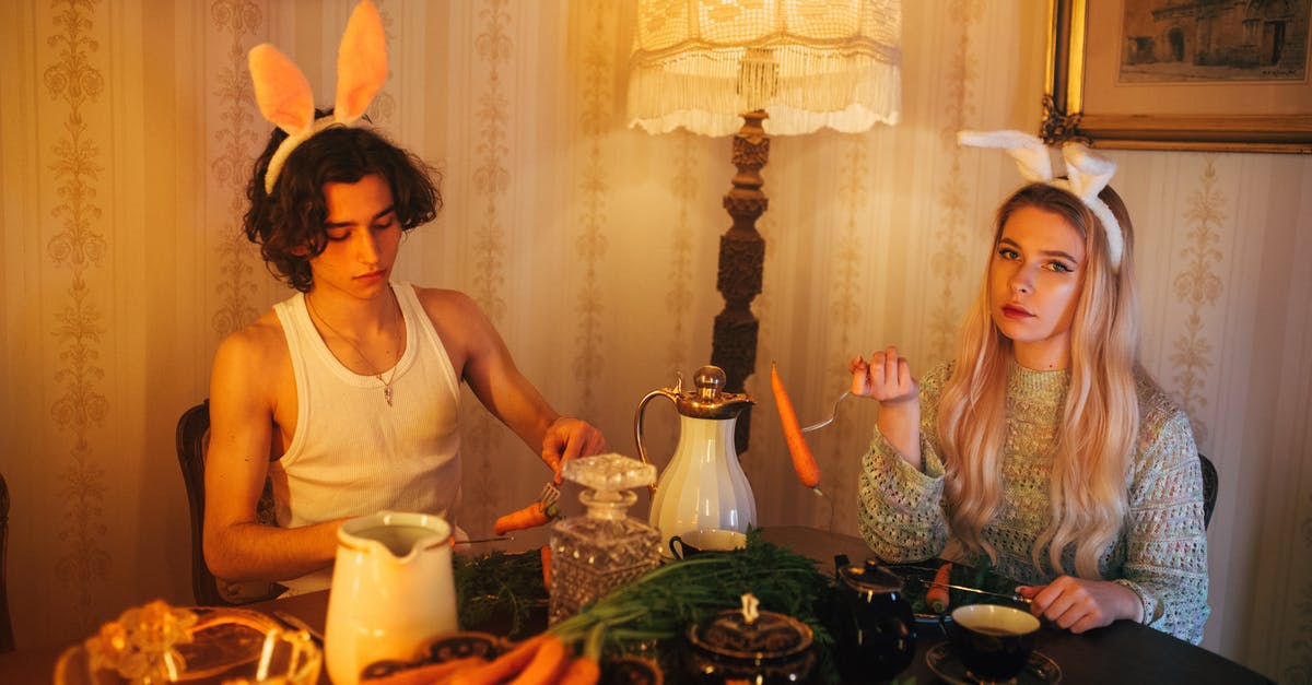 Fermented Carrots - A Boy in White Tank Top Sitting Beside the Woman in Knitted Sweater while Holding a Fork with Carrots