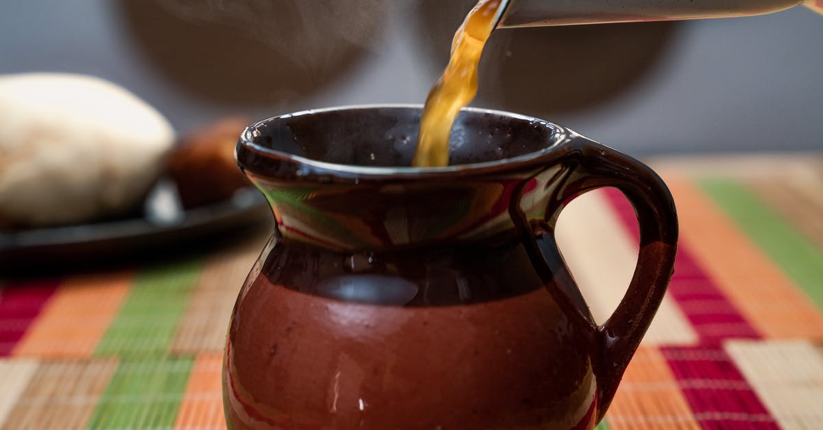 Filling a hot Kettle - Hot bouillon poured from teapot into clay jug