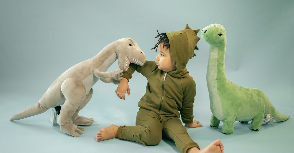 Finding good bamboo shoots - African American child with dreadlocks in dinosaur costume sitting between soft toys representing bite concept