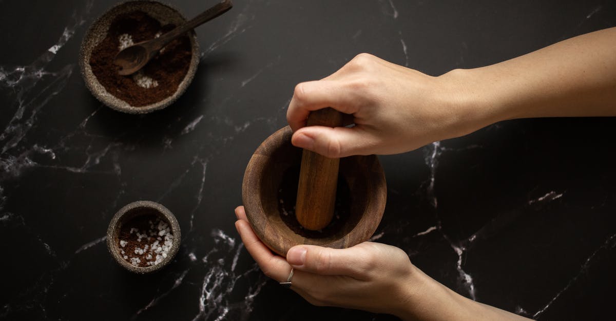 Finding the Right Coffee Grind - From above of crop unrecognizable female using pestle while grinding fresh aromatic coffee in mortar on black marble table