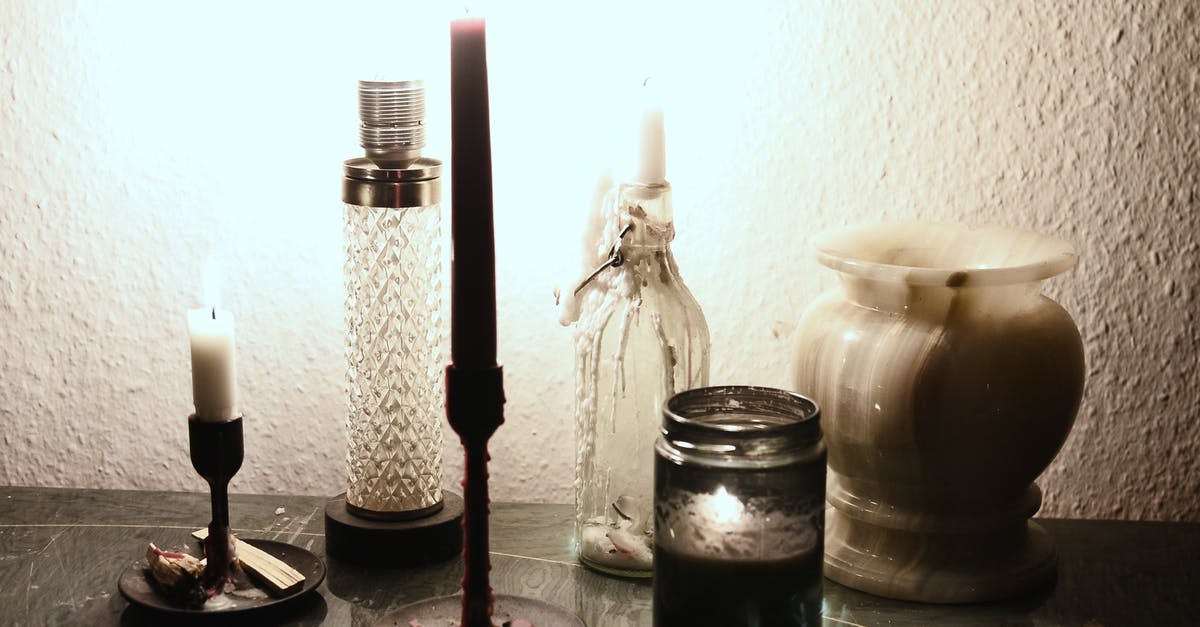 Fire under electric stovetop element - Glowing lamp illuminating dark room placed on table near burning candles on candlesticks and empty ceramic vase