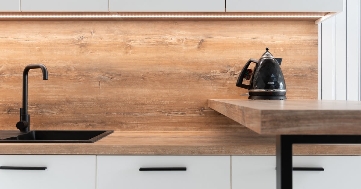 Fire under electric stovetop element - Kettle placed on wooden counter of minimalist kitchen