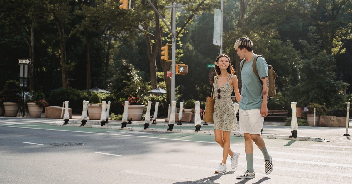 First slicing, then cooking, or the other way around? - Full body of happy young girlfriend carrying bag while walking on asphalt crosswalk with boyfriend