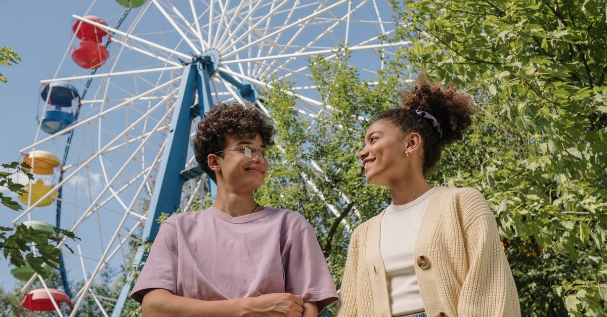 First slicing, then cooking, or the other way around? - Teenagers standing under ferris wheel and looking at each other with smile