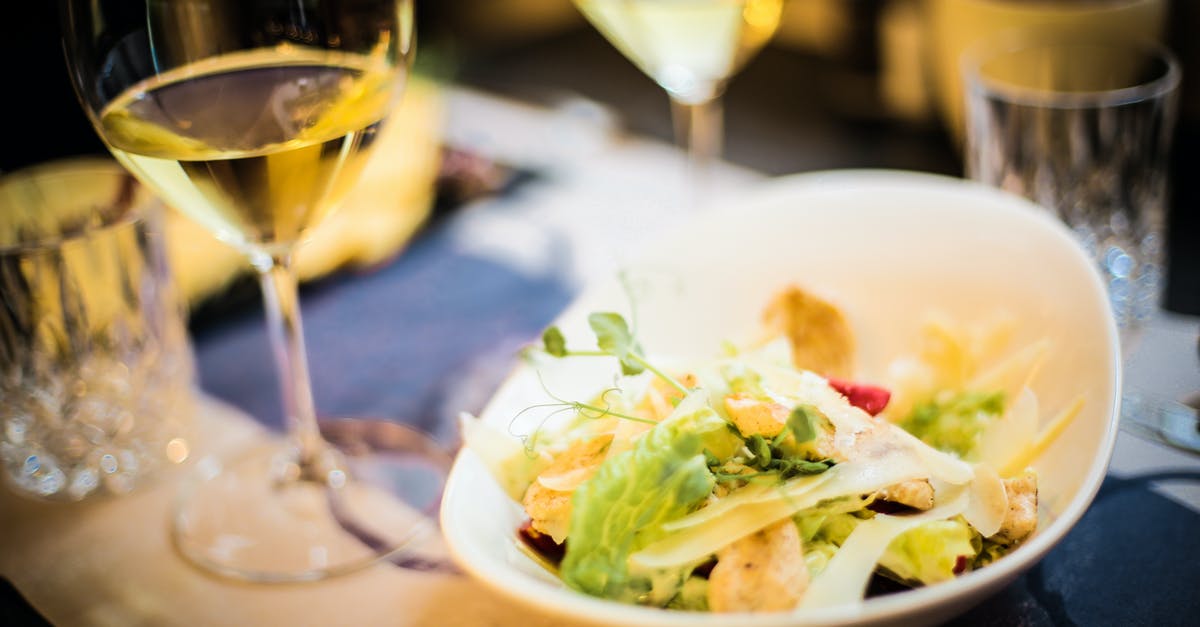 Fish always giving bitter/unpleasent taste/smell - High angle of tasty salad made of fresh vegetables and green herbs placed on table with glass of wine in luxury restaurant