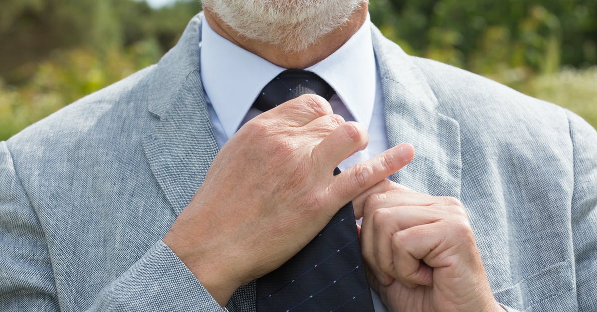 Fixing a Brownie Brick - Man in Gray Suit Jacket Holding His Necktie