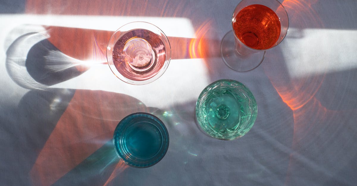 Flambe, alcohol percentage and water residue - Top view of transparent glasses filled with different beverages and placed at sun beam