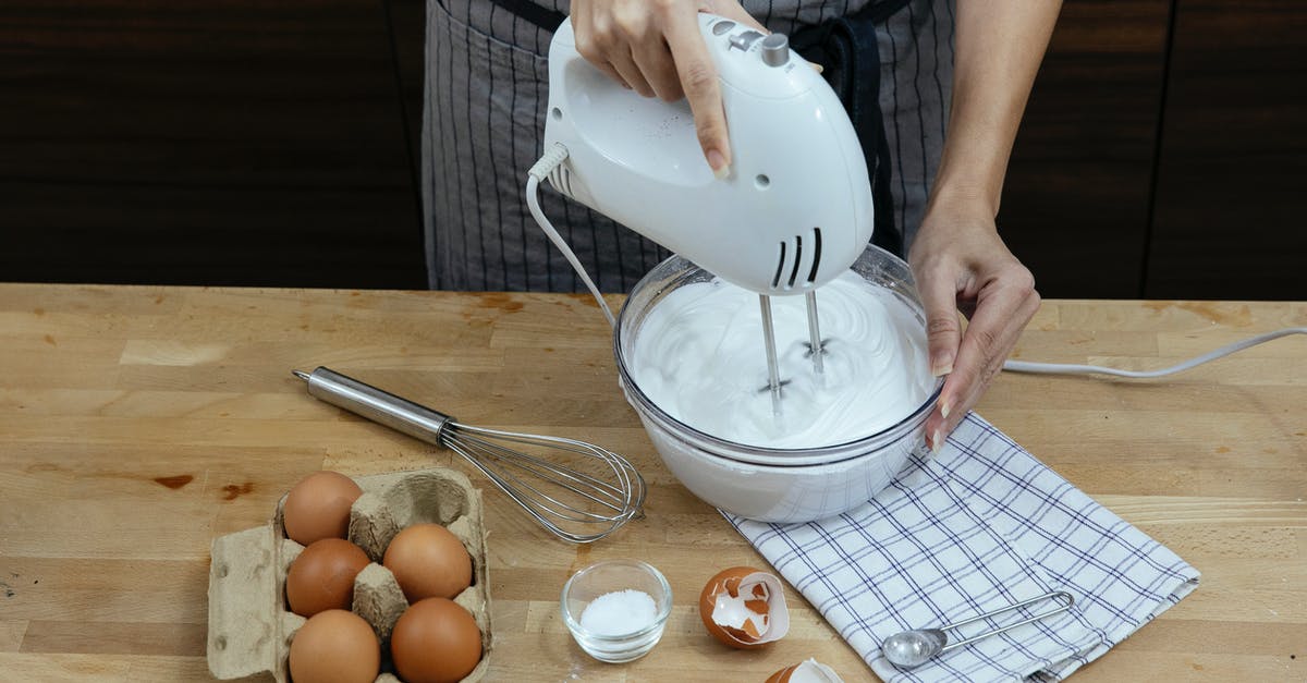 Flan recipe calls for a blender; how can I make it in a mixer instead? - High angle crop anonymous female chef in apron beating eggs and preparing fluffy whipped cream in bowl while cooking in light kitchen