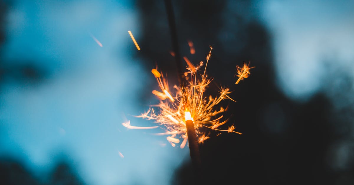 flash fire from self-cleaning oven - From below of bright burning sparkling Bengal light in park against trees and sky on blurred background