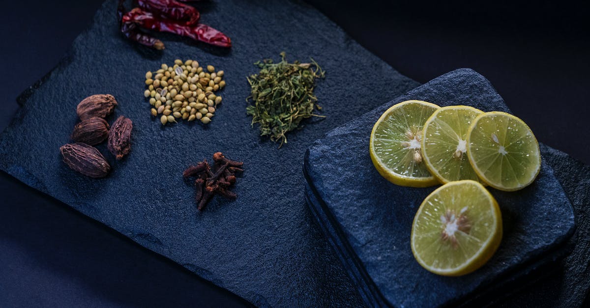 Flavor and Chemical Composition of Thyme - From above of dried chili peppers near thyme and pine nuts with cloves and ripe lemon slices on stone board