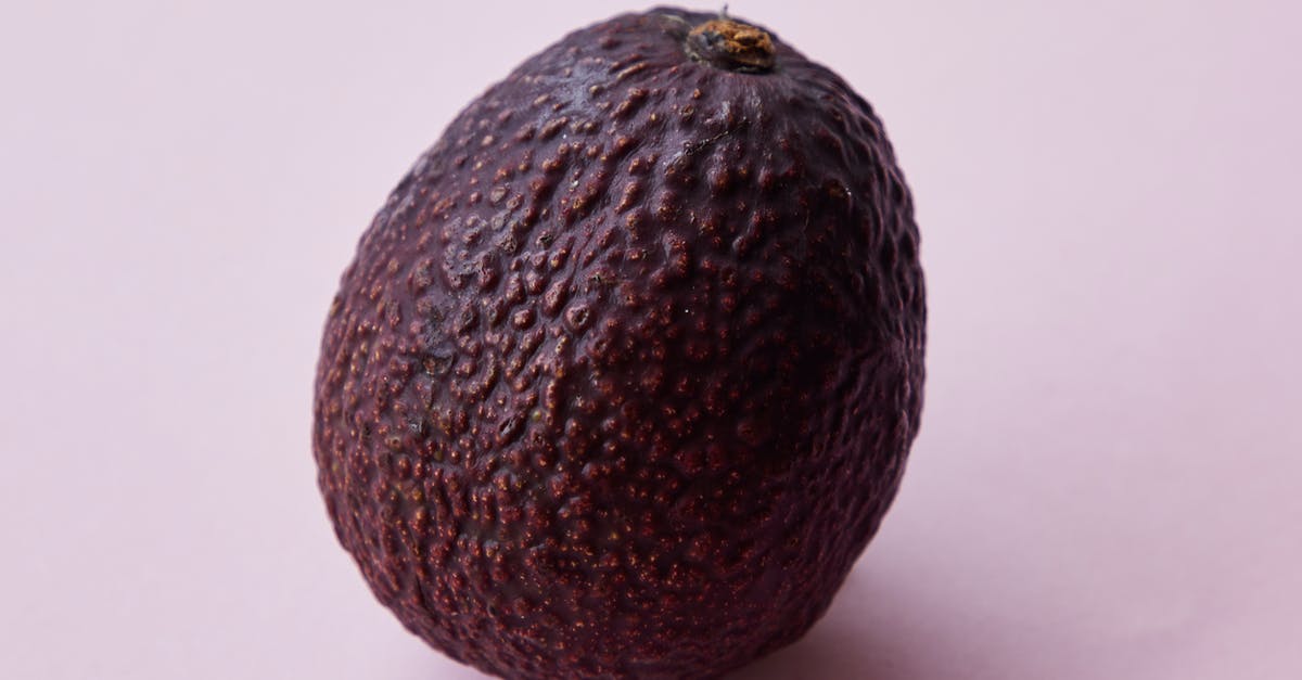 Flavor in avocadoes gone forever? - Closeup of ripe big unpeeled whole brown avocado tree fruit on purple background