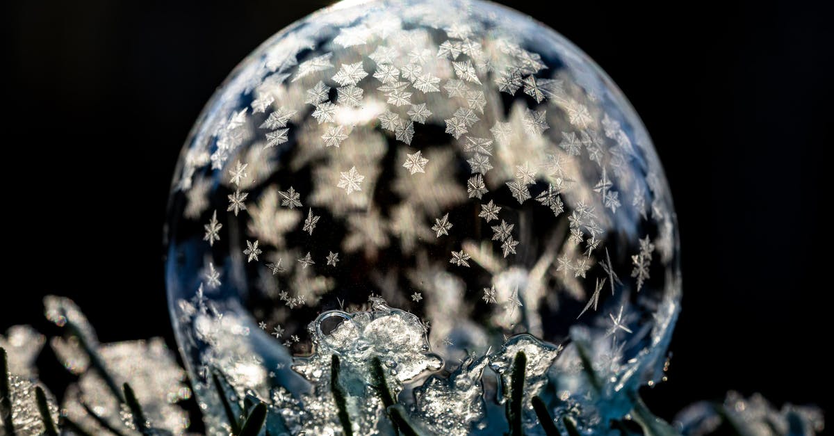 Flourless cookies form "skin" that seals in moisture - Transparent frozen sphere with ice on cold ground with hoarfrost on black background