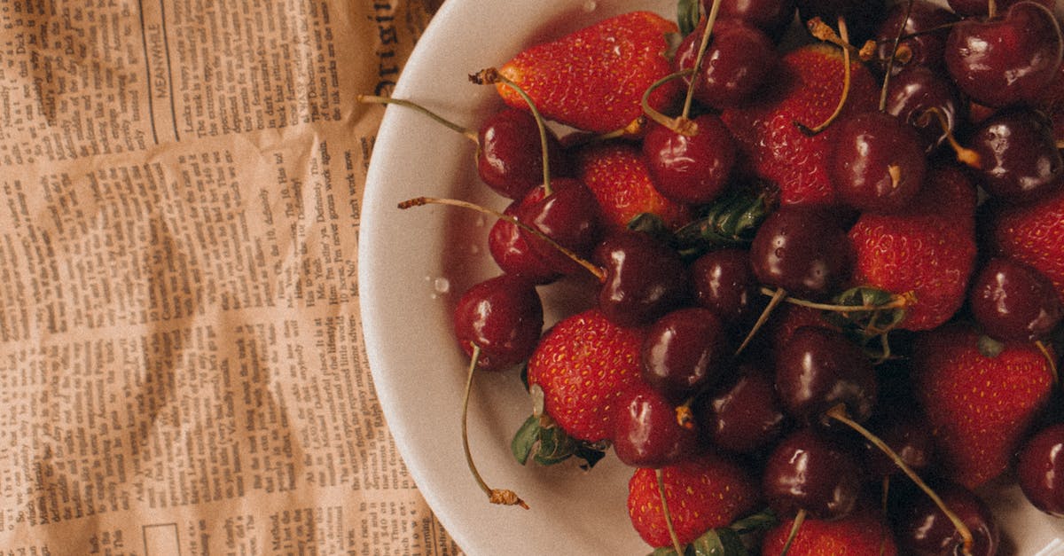 Food that does not spoil, lightweight, energetic and balanced - Strawberries and Cherries in White Ceramic Bowl on Newspaper