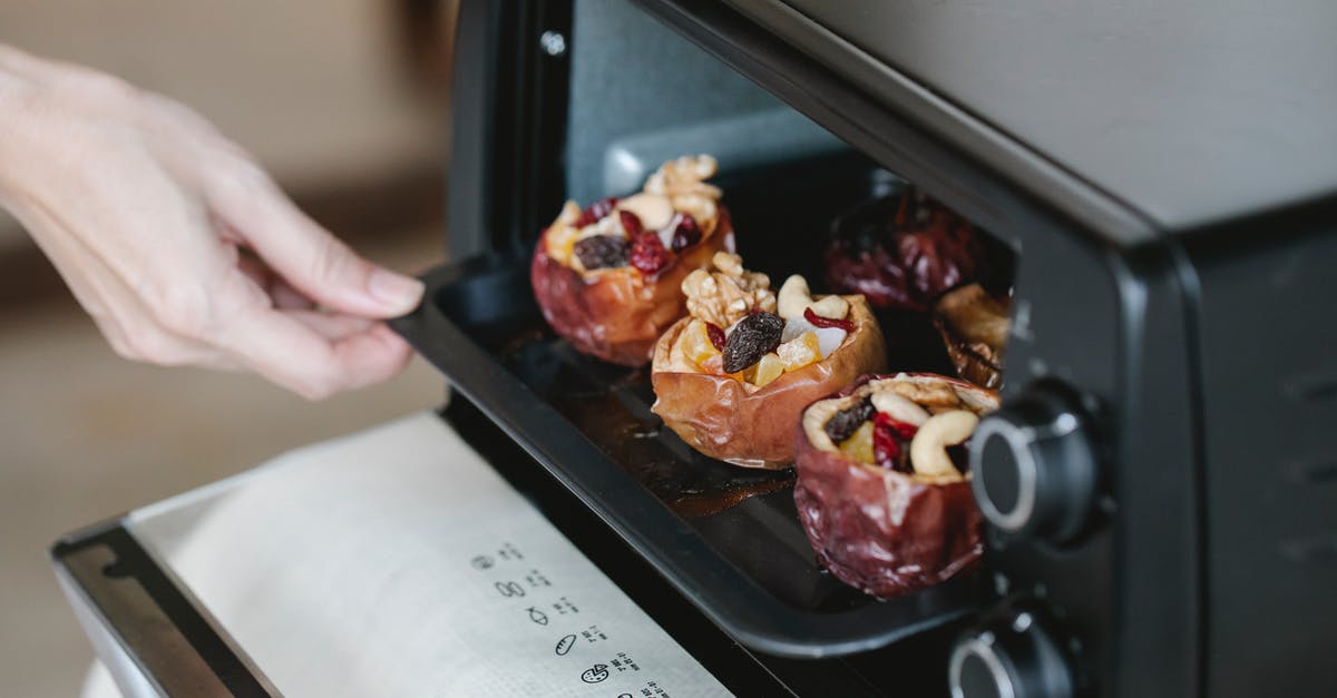 For reheating stuffing in the oven, how long would you bake it and at what temperature? - Faceless cook getting out baking tray with delicious filled baked apples of electric oven at home