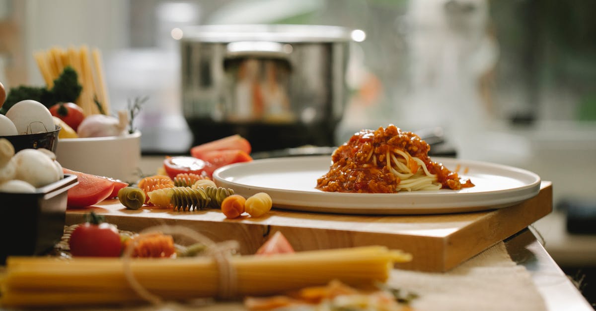 Forgot to grease ceramic pan for strata - Appetizing homemade pasta with sauce on plate placed on wooden board in kitchen with different ingredients