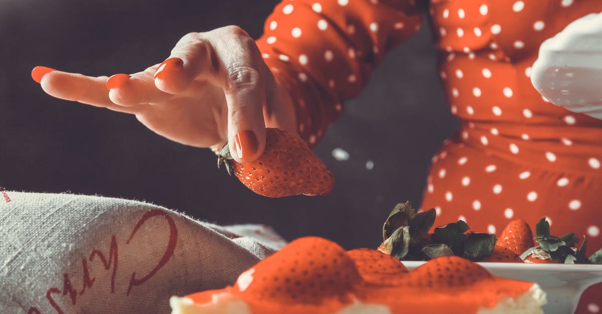 Freezing cheesecake with strawberries - A Person Holding a Strawberry