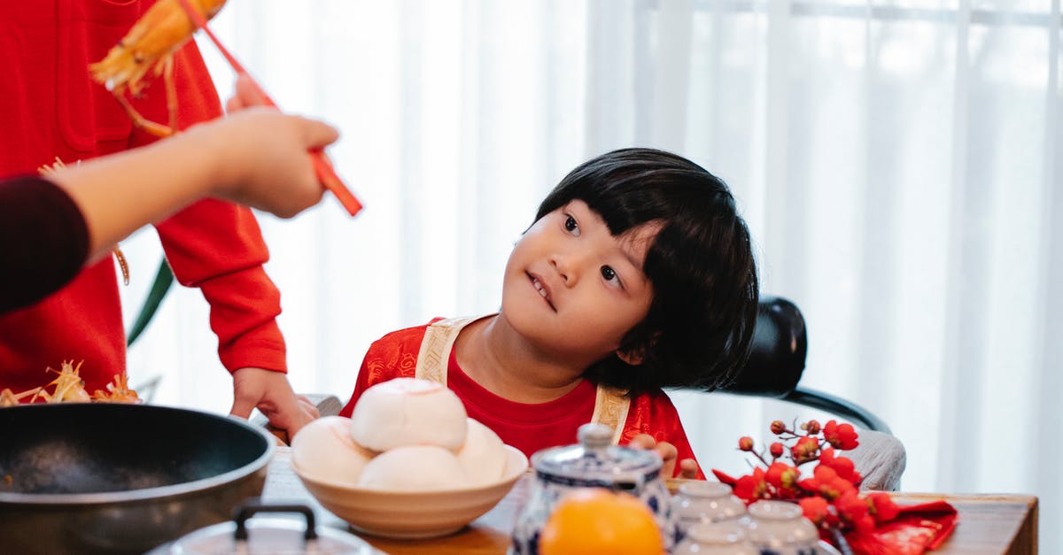 Freezing cooked rice? - Crop unrecognizable person with tasty prawn against ethnic child and relative at table during New Year holiday