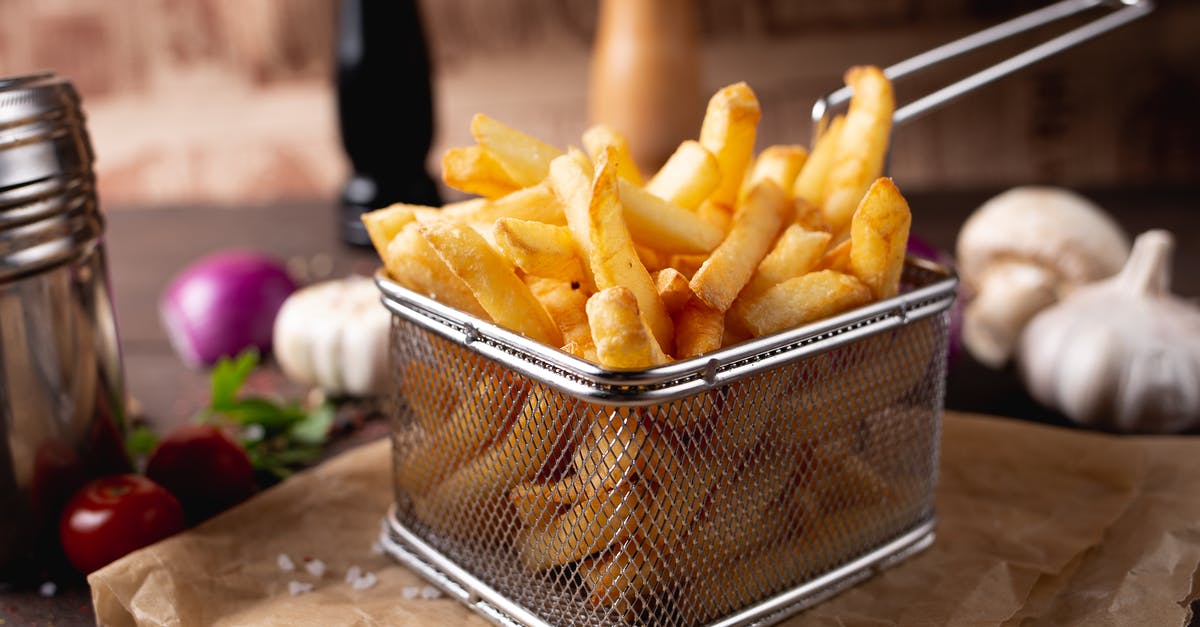 French culinary terminology for dicing vegetables - Composition of appetizing fresh french fries in steel basket placed on table amidst garlic and mushrooms