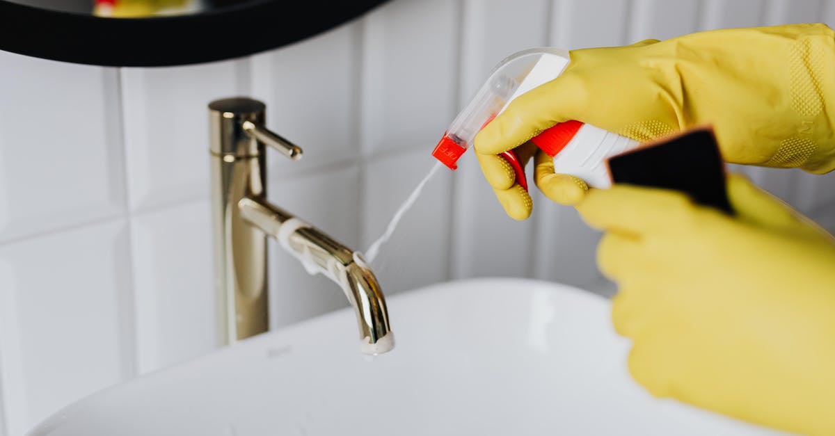 French Rolling Pin Care and Maintenance - From above anonymous housekeeper in yellow rubber gloves spraying cleaner to chrome water faucet in bathroom