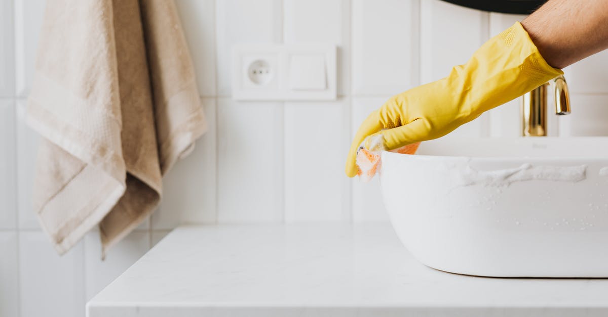 French Rolling Pin Care and Maintenance - Crop anonymous person wearing yellow latex gloves washing sink in bathroom with orange sponge and cleanser while cleaning contemporary flat