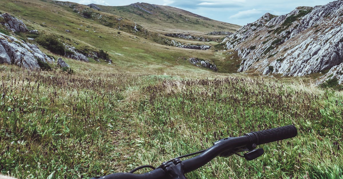 French whisk handle has rocks in it? - Person Riding Bicycle Overlooking Green Grass Field and Hill