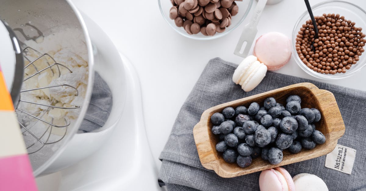 Fresh blueberries vs dried blueberries in a cookie recipe - From above composition planetary mixer macaroons wooden bowl with blueberry and chocolate disks for melting