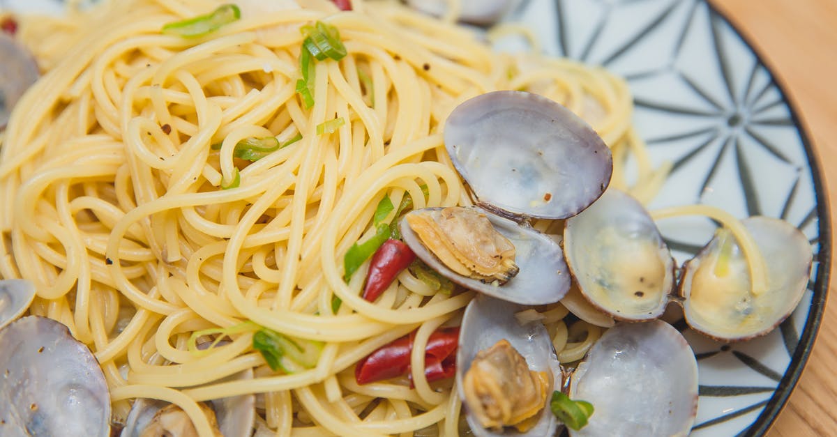 Fresh mussels, or are they? - From above of yummy spaghetti with seafood topped with green onion and red pepper served on plate placed on wooden table