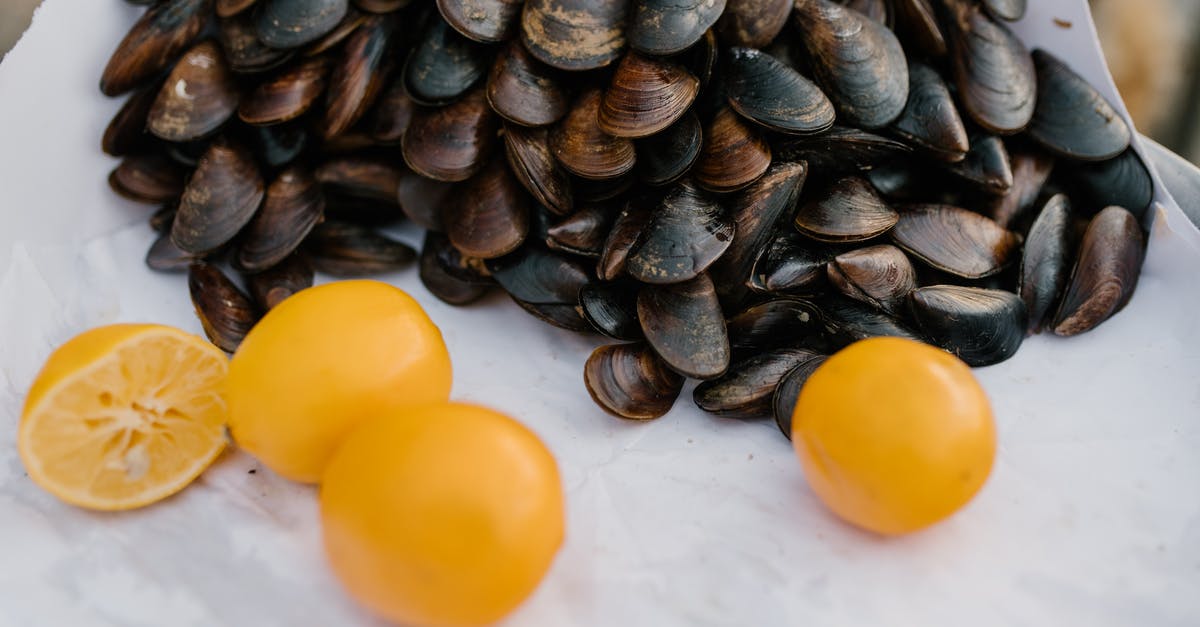 Fresh mussels, or are they? - From above of healthy ripe lemons scattered near heap of fresh mussels on white cloth in market