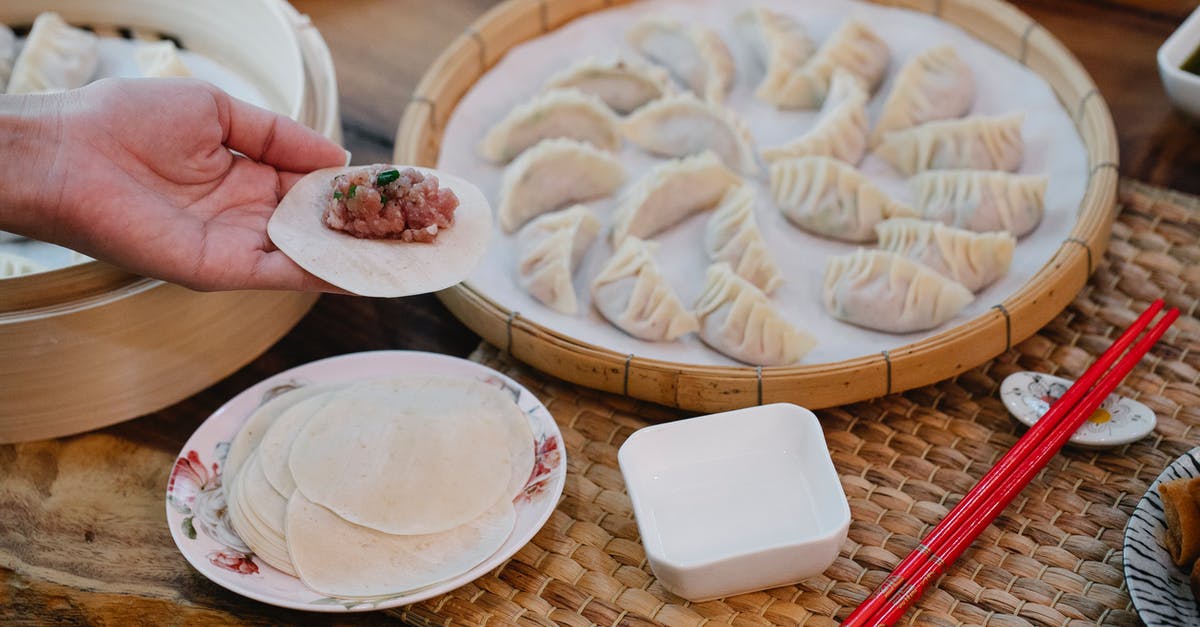 Freshly Ground Beef vs. Store Bought - From above of crop anonymous female demonstrating dough circle with minced meat filling above table with dumplings at home