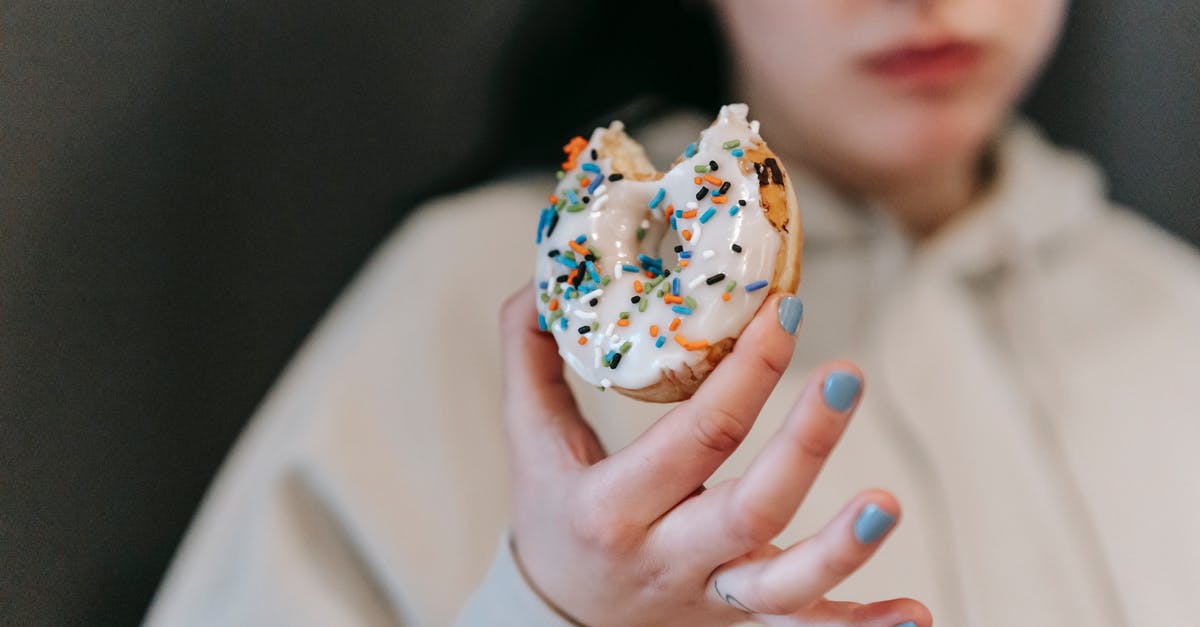 fried garam masala tastes watery - Crop blurred female wearing comfy loose clothes chewing and showing bitten tasty doughnut