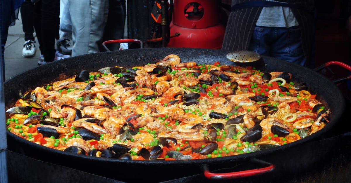 Fried rice jumps out of the pan - From above of traditional tasty Spanish dish with rice and bright chopped vegetables decorated with shellfish