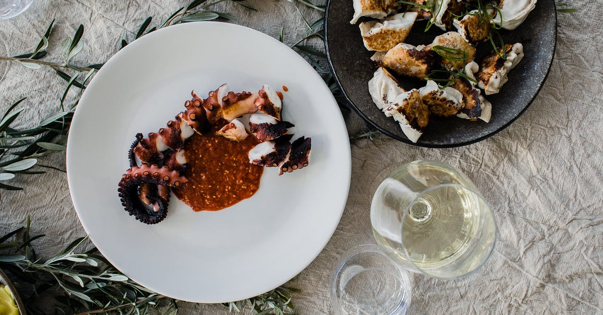 Frozen Octopus or fresh Octopus for recipes? - Top view of table served with palatable Asian dishes of octopus tentacle and gyozas dumplings with wine and soy sauce