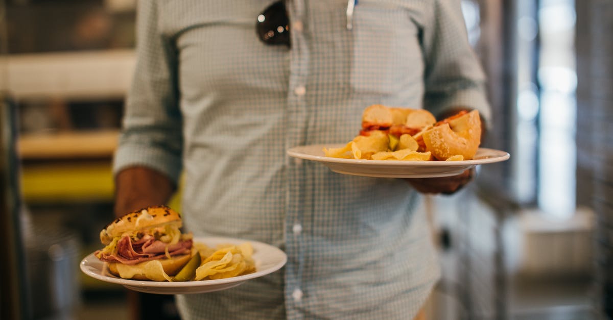 Frying donuts split along the sides - Man in Plaid Shirt Holding Two Plates with Crisps and Sandwiches