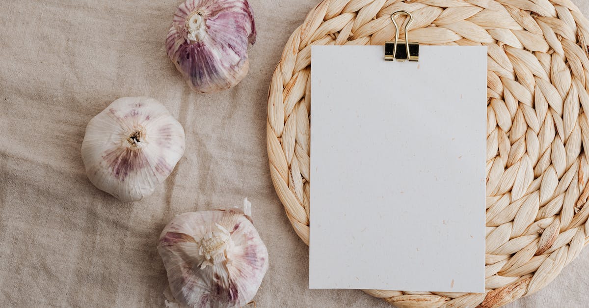 Garlic clove has turned to a firm jelly texture - Garlic and blank paper over wicker placemat on white tablecloth