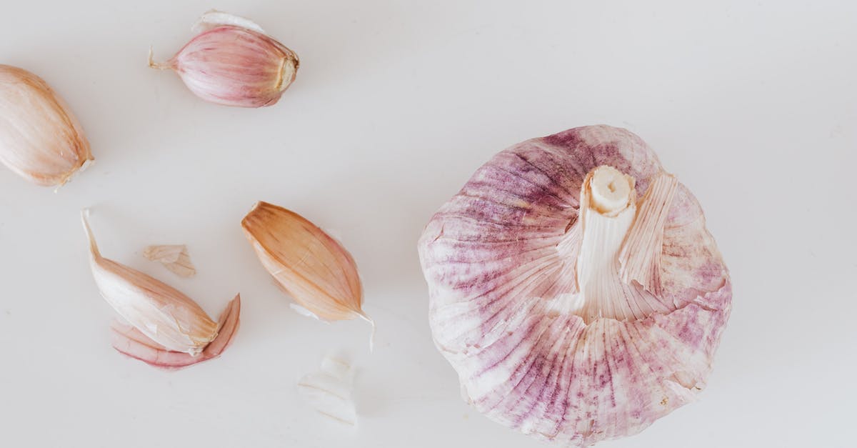 Garlic clove has turned to a firm jelly texture - From above closeup of big whole garlic and set of cloves placed on white surface