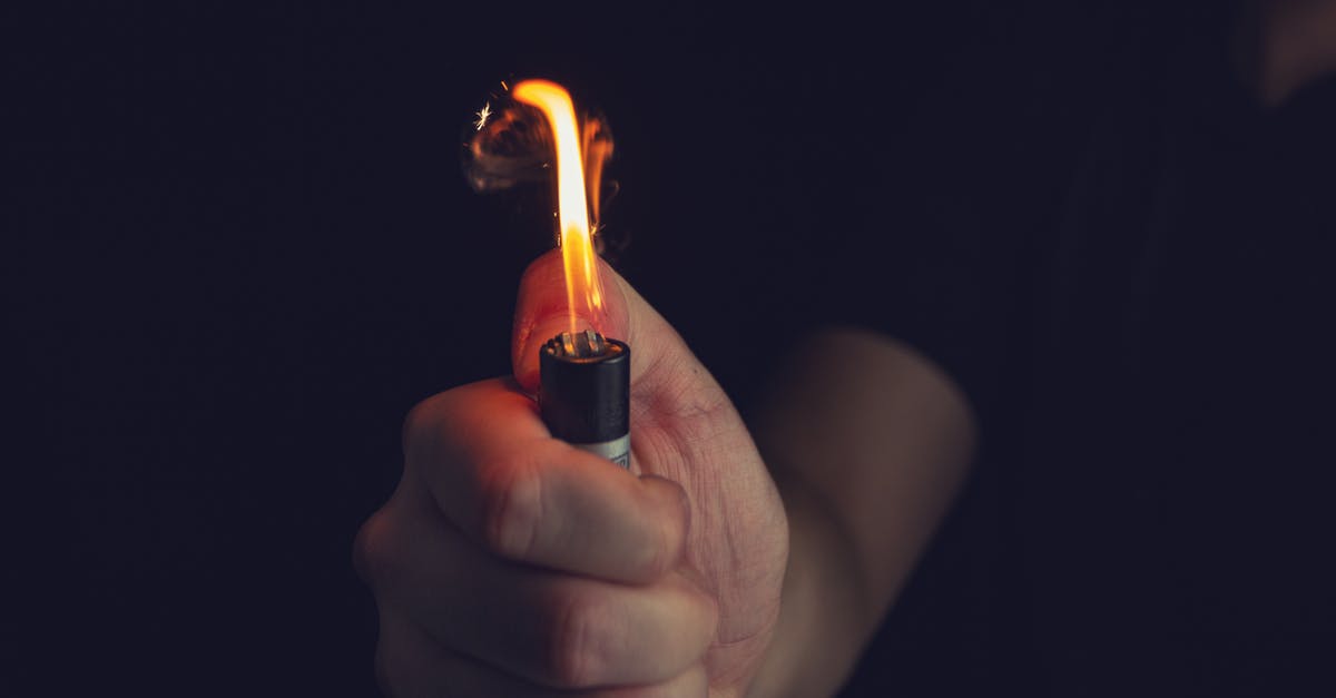 Gas grill flare up made flame covers look rusty - Crop unrecognizable man firing lighter in darkness