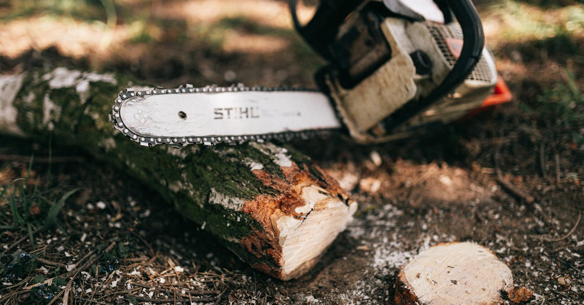 gas range hack for greater power output: does it work? - Powerful modern gas chainsaw with steel blade lying on ground near cut log and shrub in forest on sunny weather