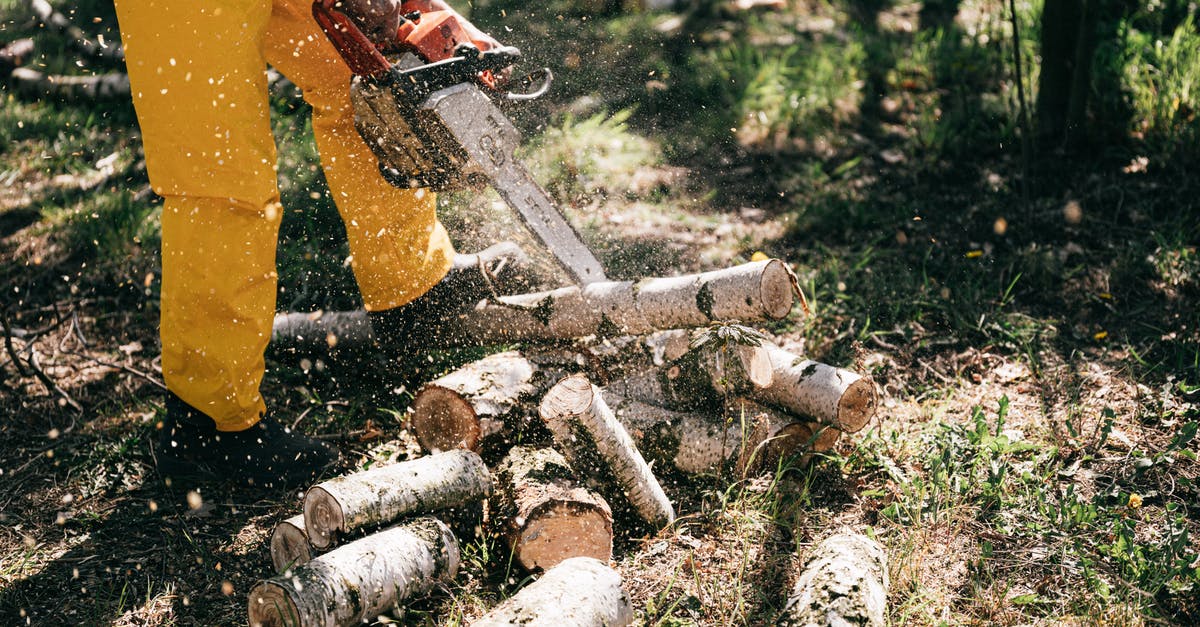 gas range hack for greater power output: does it work? - Lower body of crop anonymous person in yellow trousers lumbering log with gas chain saw in forest on summer day