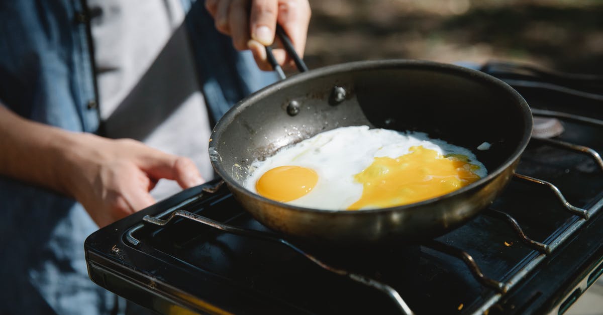 Gas stove + Wok Vs. Induction top + Skillet - From above of crop faceless male cooker frying eggs on metas gas burner using skillet in nature