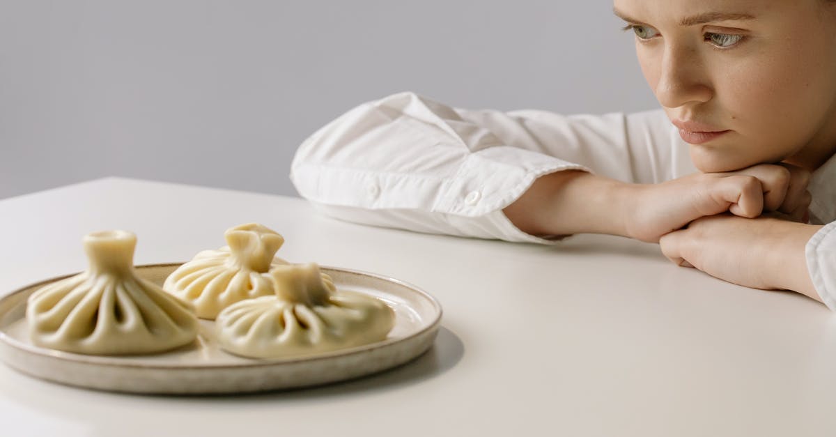 Georgian dumplings (khinkali) sticking to the bottom of the pot - Woman in White Long Sleeve Button Up Shirt Looking at the Dumplings