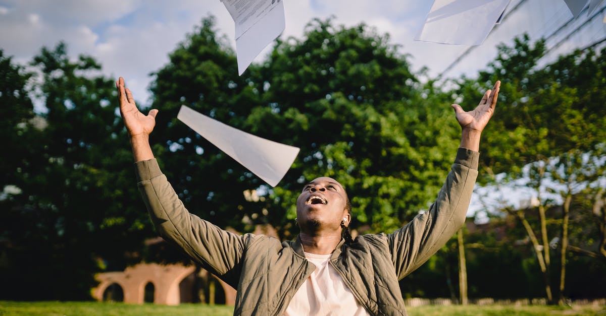 Get Grade A produce? - Cheerful young African American male student in casual clothes throwing college papers up in air while having fun in green park after end of exams
