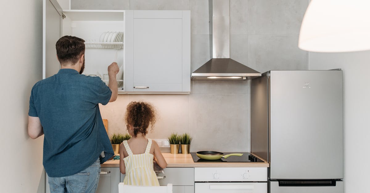 Getting better in the kitchen [duplicate] - A Man Standing Beside a Little Girl Getting Plates From the Wooden Cabinet of the Kitchen 