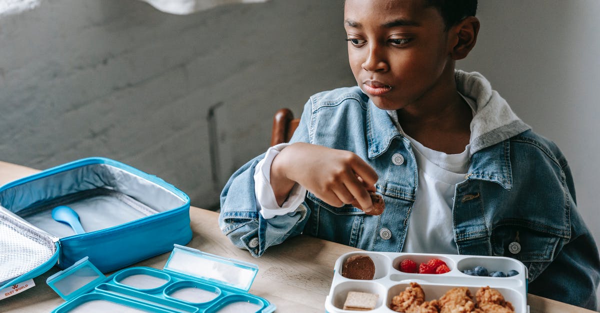 Getting biscuit mix to rise...again - Crop contemplative African American schoolchild looking away at table with lunch container full of yummy food